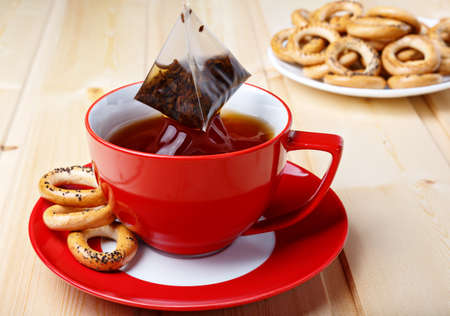 Tea bag splash in a red mug, close-up, on background of drying with poppy seeds.の写真素材