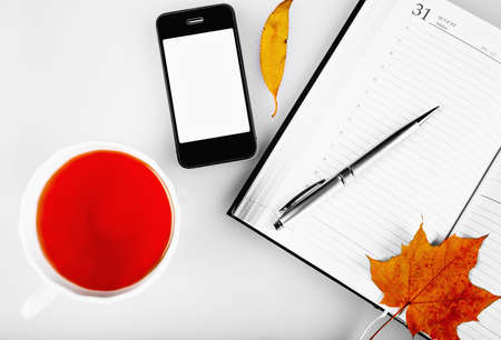 Grip with notepad, with a gray background with yellow maple leaves.の写真素材