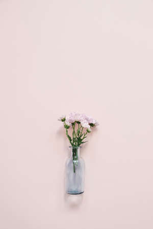 Beautiful blue glass vase with small pink bouquet on pink background.の写真素材