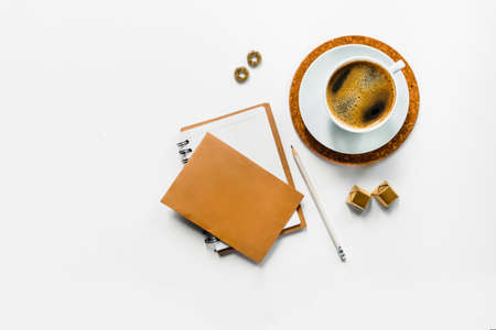 White desktop with cup of coffee and notebook and envelope. Plase to your text.