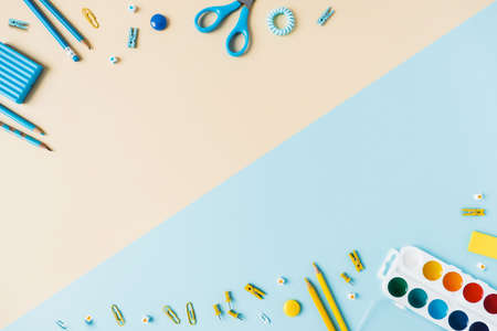 Blue yellow school desk with pencils, pencil case, paper clips, watercolor paints. Top view with...