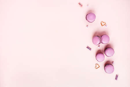 Pink background with macaroons surrounded by hearts. Top view with space for your text.