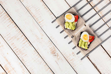 Two diet sandwiches with avocado, tomato, cream cheese on white wooden background. Food for vegetarians. Space for your text. Flat lay, top view.の写真素材