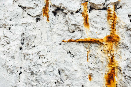 A white stone wall with rusty bits of rebar sticking out.の写真素材
