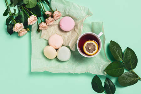 Food-drink mint concept. Tasty marshmallows wrapped in paper with cup of hot tea with lemon. Flat...