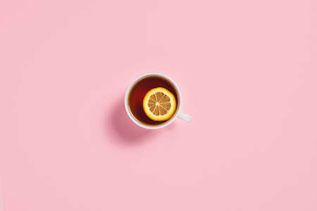 Pink background with cup of tea and lemon on a pink background. Flat lay, top view, copy space.の写真素材