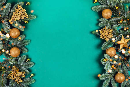 New year and Christmas concept. Frame of Christmas tree branches decorated with gold ornaments and lights. Flat lay, top view, copy space.の写真素材