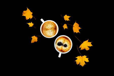 Two cups of coffee on a black isolated background with maple leaves. Flat lay, top view.の写真素材