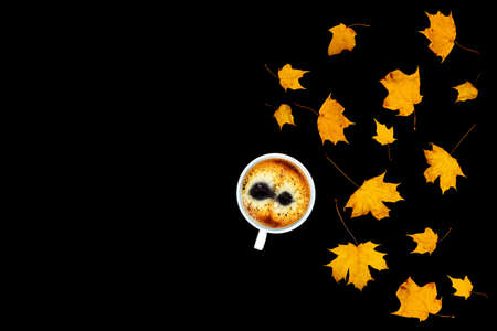 Cup of coffee on a black isolated background with maple leaves. Flat lay, top view, copy space.の写真素材