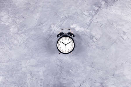 Black vintage clock with alarm on gray concrete background. Flat lay, top view, copy space.の写真素材