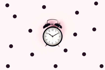 Alarm vintage clock on a pink background surrounded by confetti. Flat lay, top view, copy space.の写真素材