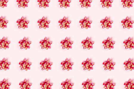 Christmas and new year pattern. Celebration picture. Pink background with red bright bows. Flat lay, top view.の写真素材