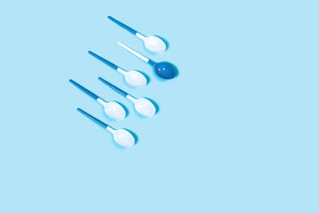 Concept of white plastic spoons on blue background. Flat lay, top view.の写真素材