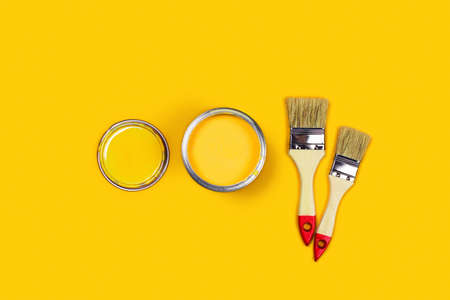 Renovation concept. Yellow background with paint can, cap and brushes. Flat lay, top view, copy...