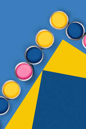 Renovation concept. Blue and yellow background with group of colored paint cans. Flat lay, top view,...
