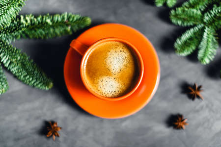 Christmas and New year composition with orange cup of coffee surrounded by fir brunches with red balls and lights on gray table.の写真素材
