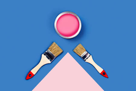 Renovation picture. Blue and pink background with one pain can and two brushes, diagonal composition. Flat lay, top view, copy space.の写真素材