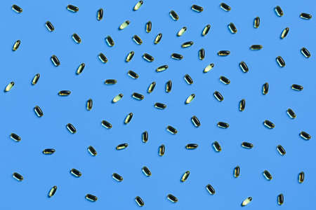 Medical blue background. Fish oil capsules on a table. Flat lay, top view.