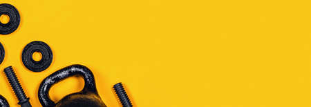 Sports web-banner. Kettlebell and dumbbell on yellow background. Flat lay, top view, copy space.