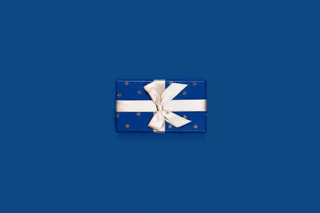 Gift box with surprise on classic blue background. Flat lay, top view.