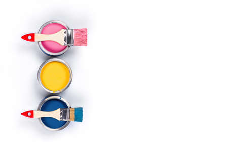 Renovation picture. Isolated white background with three pink, yellow and classic blue pain cans and two brushes. Flat lay, top view, copy space.の写真素材
