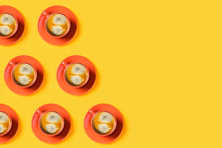 Yellow background with orange cups of tasty coffee. Flat lay, top view, copy space.
