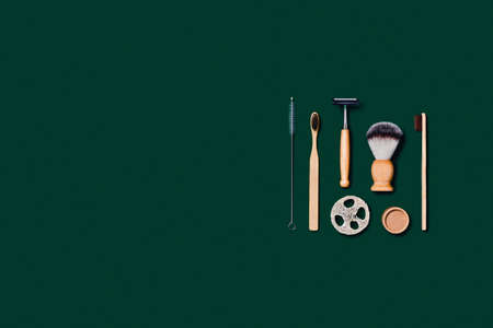 Zero waste concept. Natural bamboo toothbrush, razor, paper tube, natural sponge on green...