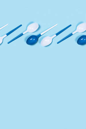 Dangerous plastic spoons on vertical picture. Environmental problem of plastic rubbish pollution. Flat lay, top view, copy space.の写真素材