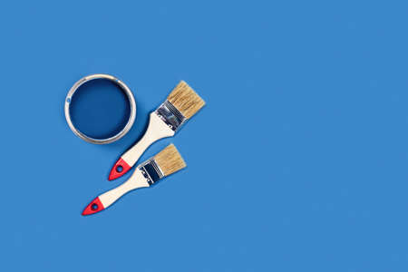 Photo for apartment repairs. Blue background with paint can and two wooden tassels.の写真素材