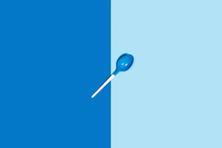 Picture of white plastic spoons on blue background. Flat lay, top view.の写真素材