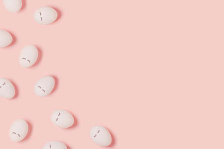 Happy Easter. Pattern with white eggs with painted eyes on a pink background. Flat lay, top view, copy space.の写真素材