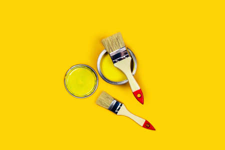 Renovation picture. Yellow background with one paint can and two brushes. Flat lay, top view, copy...