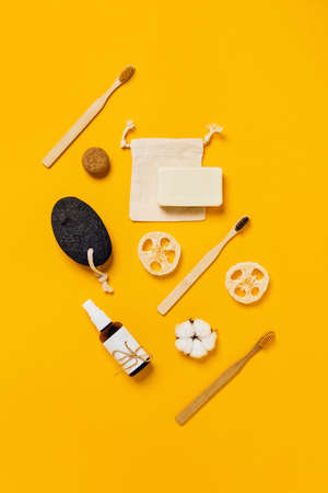 Vertical photo in yellow tones. Ecological accessories for the kitchen and bath: natural sponges, bamboo toothbrush, shaving brush and rag bag.の写真素材