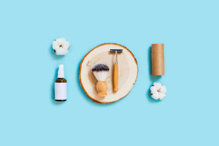 Zero waste concept. Craft tube, wooden tray, natural oil in the spray glass bottle, shaver, shaver brush on blue background. Flat lay, top view, copy space.の写真素材