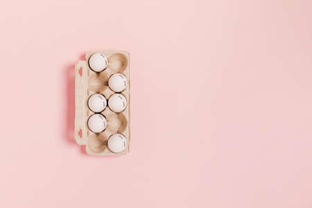 Happy Easter. White eggs with painted eyes in paper packaging on pink background. Flat lay, top...