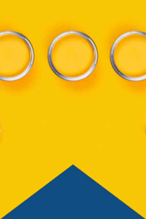 Repair concept. Yellow background with three paint cans. Flat lay, top view, copy space.