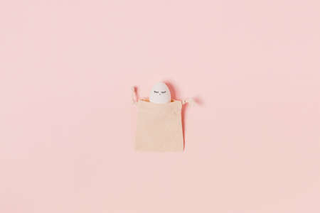 Happy Easter. White egg with painted eyes in the rag bag. Flat lay, top view, copy space.