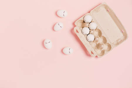 Happy Easter. White eggs with painted eyes in paper packaging on pink background. Flat lay, top...