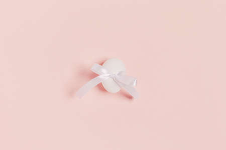Happy Easter. One white egg inside ribbon bow on pink background. Flat lay, top view, copy space.の写真素材