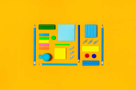Yellow background with rectangle-shaped writing materials for school and university. Flat lay, top...