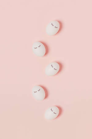 Happy Easter. White eggs with painted eyes on pink background, vertical picture. Flat lay, top view, copy space.の写真素材
