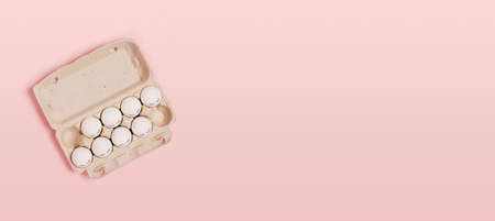Happy Easter. White eggs with painted eyes in paper packaging on a pink background. Flat lay, top...