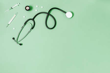 Medical green background with stethoscope, thermometer, syringe and tablets.の写真素材
