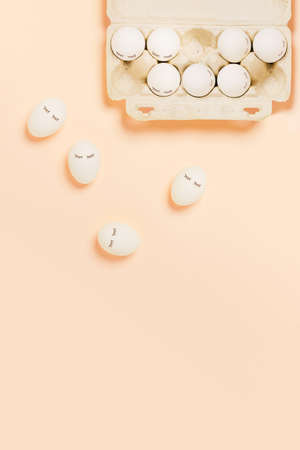 Festive Easter peach color background with white eggs and eyes drawn on them. The inscription is a...