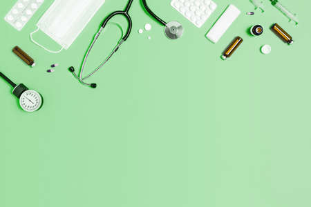 Medical mint green background with different accessories: stethoscope, thermometer, syringe and tablets.の写真素材