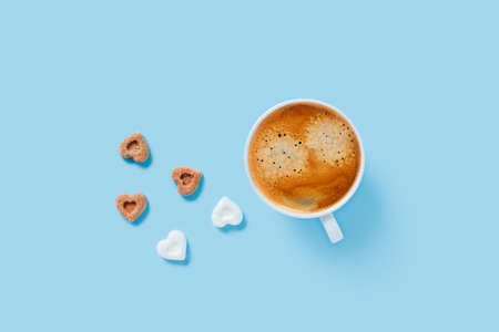 Morning cup of strong coffee with five pieces of sugar in the shape of hearts on blue background.の写真素材