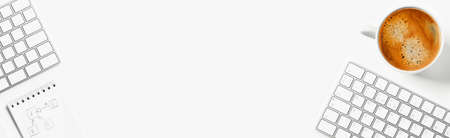 Home office. A white desktop with a keyboard, notepad and a cup of delicious coffee.の写真素材