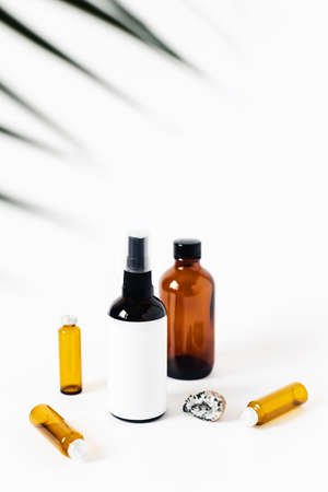 Two glass spray bottles on white background surrounded by crystal of quartz, the vials and herbs.の写真素材
