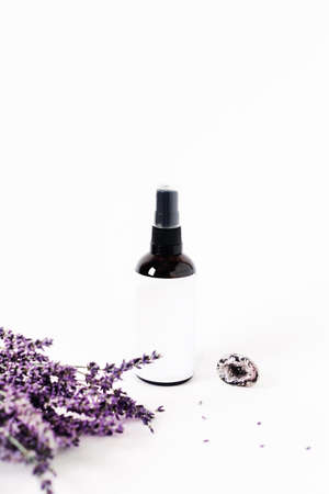 Glass spray bottle on white background surrounded by lavender bouquet and the crystal of quartz.の写真素材