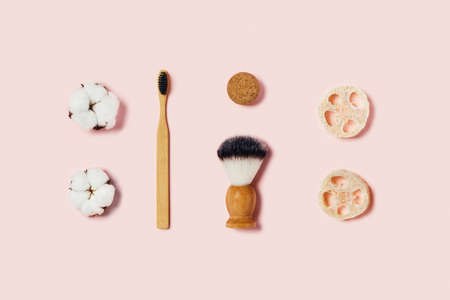 Bathroom accessories on pink background. Natural bamboo toothbrush, sponges, cotton flowers, shaving brush. Flat lay, top view.の写真素材